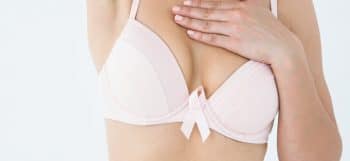 woman in pink bra checking breast